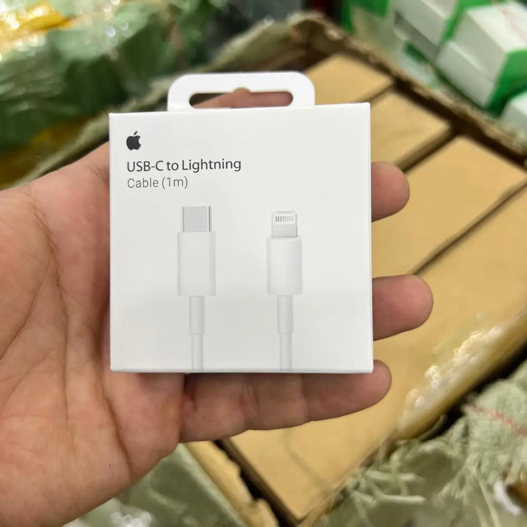Hand holding a white USB-C to Lightning cable packaging with Apple logo.