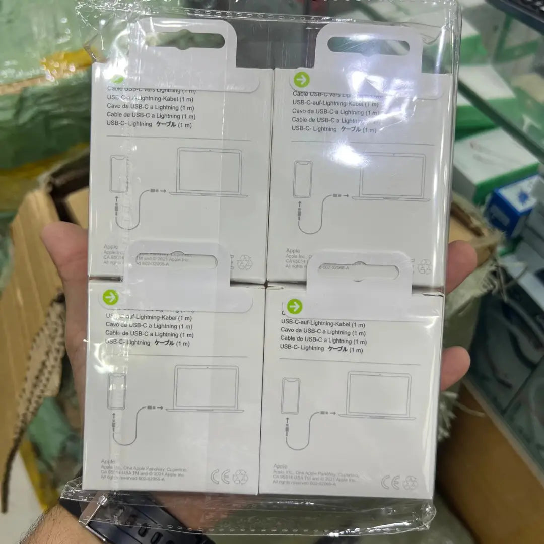 Packaged USB-C to Lightning cables held in a hand with a blurred background