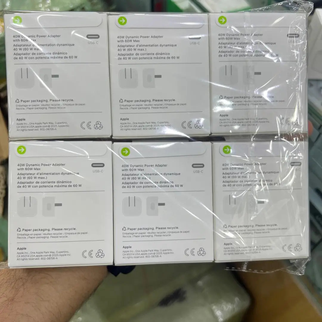 Multiple boxes of Apple power adapter packaging on a shelf.

