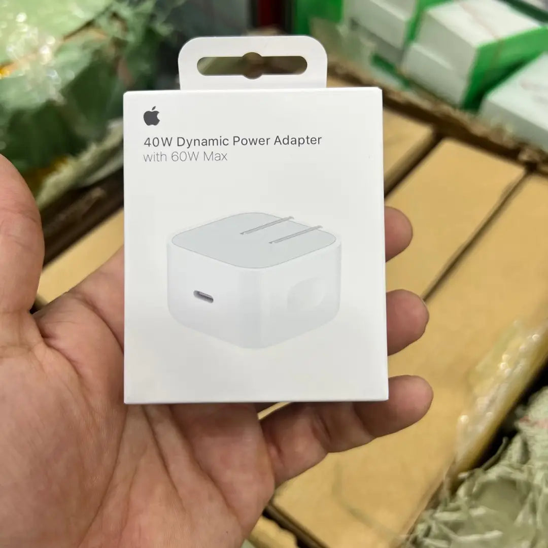 Hand holding a 40W Dynamic Power Adapter packaging with Apple logo.
