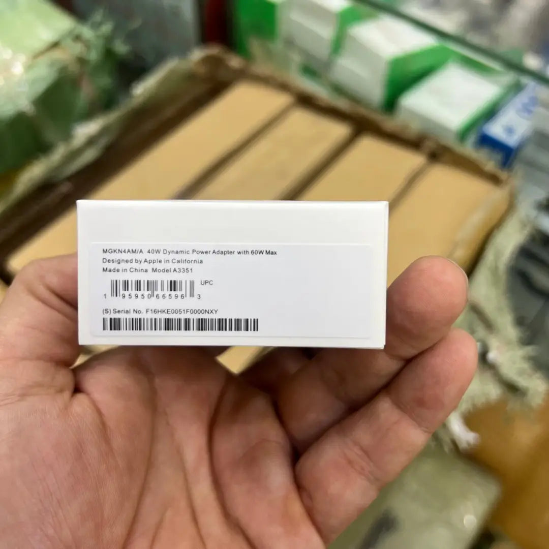 Hand holding a white label with text and barcodes against a blurred background