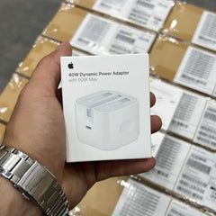Hand holding a 40W Dynamic Power Adapter box with Apple branding against a background of similar boxes.

