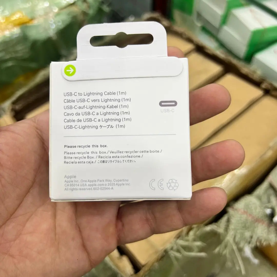 Hand holding a white Apple USB-C to Lightning cable packaging